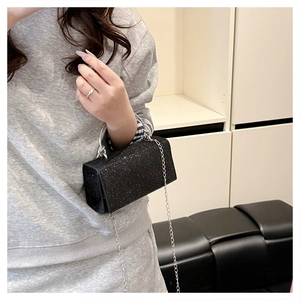 Close-up of black glitter clutch with silver ring handle and delicate chain strap