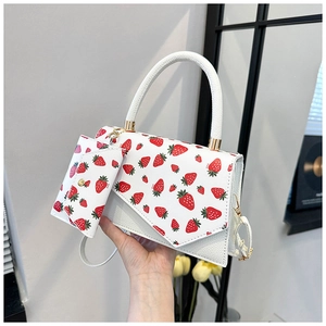 Detail of strawberry print crossbody bag with asymmetric flap and matching small pouch