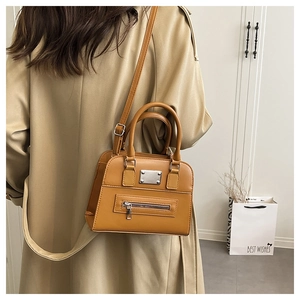 Detail view of camel vintage leather Boston bag with metal plaque and zip pocket