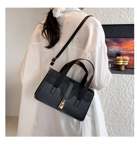 Detail of black sequined crossbody bag showing matte texture and gold buckle on model