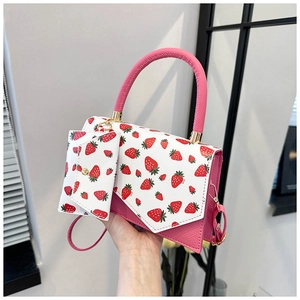 Detail of pink and white strawberry print shoulder bag with gold hardware and mini pouch