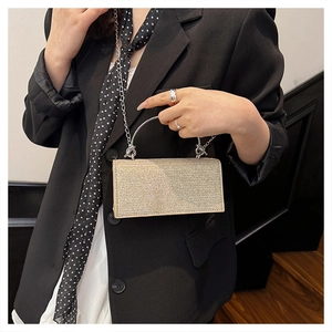 Detail of a sparkling gold sequin evening clutch bag with round metal handle and chain strap