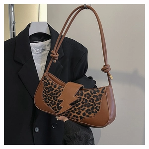 Primer plano de bolso bajo el brazo con estampado de leopardo y hebilla de rayo