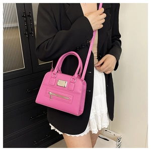 Detailed shot of a pink leather Boston bag with metal plate and adjustable strap