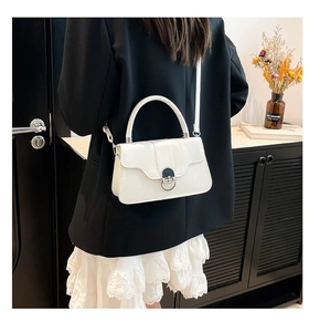 Detail of white leather shoulder bag featuring silver metal twist lock and sleek handle
