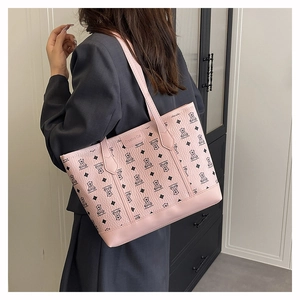 Detail of pink tote bag with bear pattern and leather texture worn by a model
