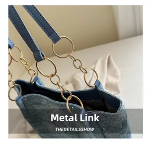 Detail of light blue glittery denim tote bag featuring golden metal chain and leather strap