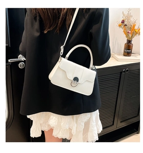 White shoulder bag featuring wave-edge flap and silver round metallic twist-lock detail