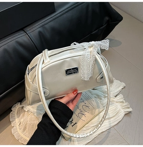 Dettaglio borsa bowling bianco crema con fiocco in pizzo e placchetta in metallo