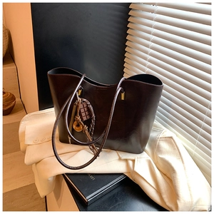 Macro detail of dark brown leather tote featuring creative chocolate-shaped charms