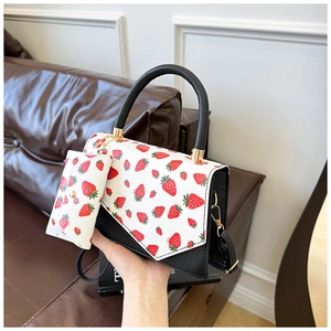Detail of strawberry print shoulder bag with lychee grain texture and matching pouch