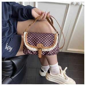 Detail of vintage polka dot canvas bag with white crochet lace trim and leather buckle