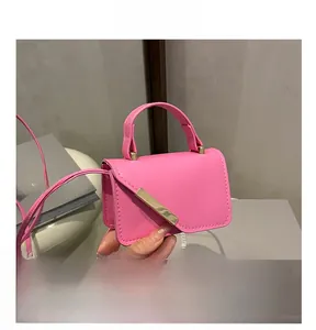 Detail of pink PU leather mini square bag with gold metal trim and slim shoulder strap