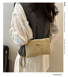 Detail of hand-woven beige straw envelope bag with gold zipper and stylish wrist strap