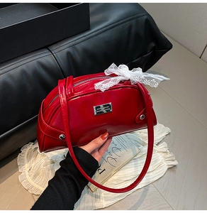 Dettaglio della borsa bowling in vernice rossa con fiocco in pizzo bianco e targhetta argento