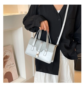 Detail of silver crossbody bag with glitter finish and elegant metal twist lock closure