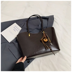 Detail of dark brown leather tote bag with vintage charm and gold hardware on white fabric
