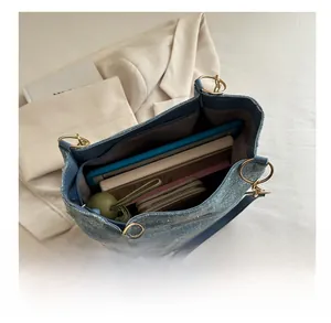 Blue denim tote bag showing spacious interior with tablet, notebook, and folding umbrella