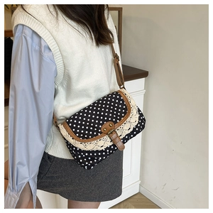 Polka dot crossbody bag with vintage lace trim and leather strap worn by a model
