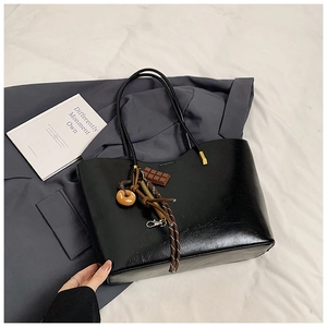 Close-up of black tote bag with polished finish and cute donut chocolate charms