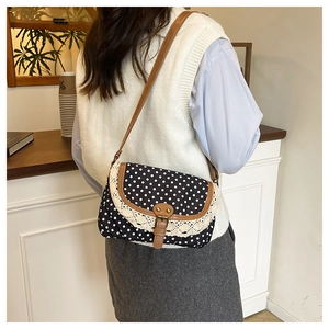 Detail of vintage polka dot canvas bag with lace trim and brown leather shoulder strap