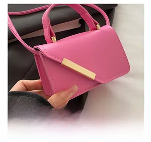 Detail shot of hot pink mini handbag with gold metal bar and premium leather texture