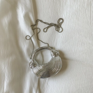 Detailed macro view of silver metallic shell with wave texture and bead chain strap