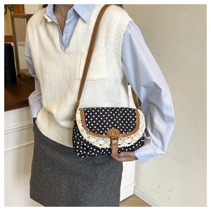Close-up of vintage black polka dot bag featuring white lace edges and retro metal buckle