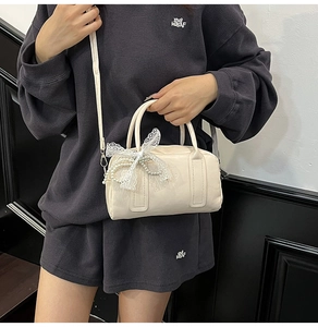 Chic cream Boston bag detail with lace bow and pearl chain on a stylish shoulder strap