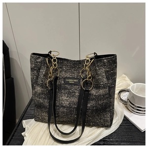 Detail of glittery fabric tote bag with gold chain and black leather handle