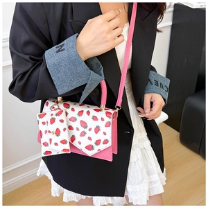 Detail of pink strawberry print crossbody bag with mini pouch on a model's waist