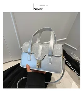 Detail view of silver mini handbag with shimmering glitter flap and gold metal twist lock