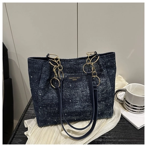 Close-up of blue denim tote bag with gold chain strap and chic star pattern detail