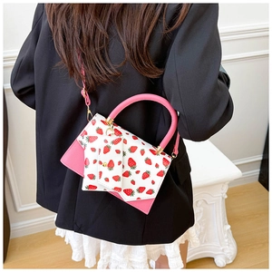 Detail of white leather shoulder bag with strawberry print and pink handle on model
