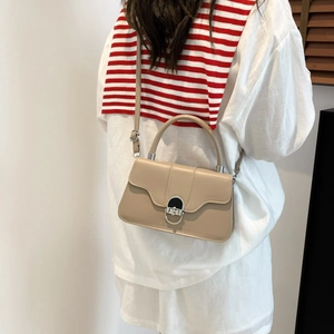 Beige leather underarm bag with silver hardware lock and adjustable strap for women
