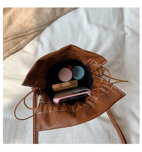 Detail view of brown PU bucket bag interior showing space for phone and makeup items
