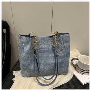 Detail of light blue denim tote bag with shimmering rhinestones and gold chain strap