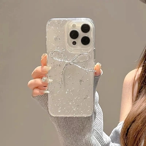 Close-up of clear iPhone case with silver glitter and a 3D metallic bow decoration