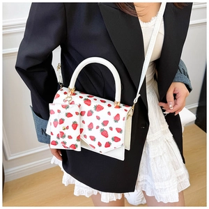 Detail of white crossbody bag with strawberry print and matching mini charm pouch