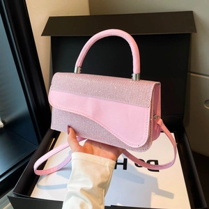 Pink sequin saddle bag with curved flap and leather strap on luxury gift box