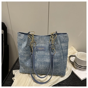 Detail of light blue denim tote bag with rhinestone studs and gold chain strap