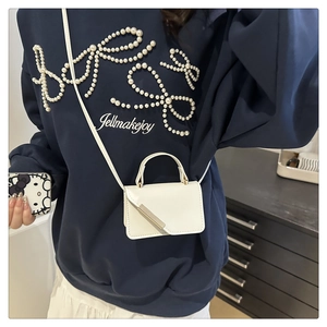 Mini white crossbody bag with gold metal trim shown on model for size perspective