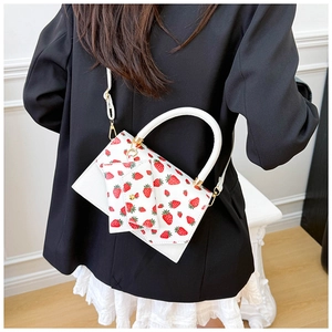 Close-up of white leather shoulder bag with strawberry print and gold chain strap