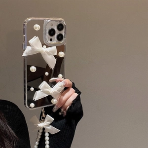 Detail van iPhone spiegelhoesje met witte parels en zijden strik polsbandje