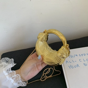 Modern golden crescent handbag with metallic texture and circular handle shown in hand