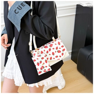 Detail of white strawberry print handbag with matching mini card pouch and gold hardware