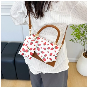Detail of strawberry print shoulder bag with matching coin purse and gold hardware