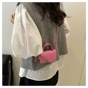 Detail view of pink mini crossbody bag with minimalist gold metal bar and flap closure