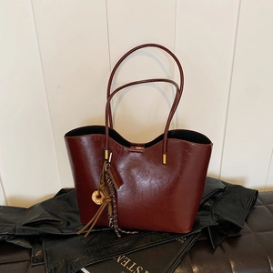 Minimalist burgundy leather tote bag with vintage tassel charm on a casual setting
