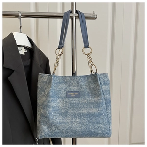 Detail of blue denim tote bag with shimmering rhinestones and golden chain handle